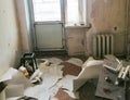 A room with bare walls and torn wallpaper, dirt, dust, debris