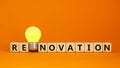 Renovation symbol. Wooden cubes with the word `renavation`. Yellow light bulb. Beautiful orange background. Business and