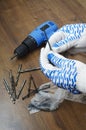 Renovation work indoor.Man holding huge bolt against wooden floor.Screwdriver and drills on the floor.Vertical shot