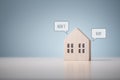 Rent or Buy home choice question with wooden model house on blue background Royalty Free Stock Photo