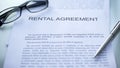 Rental agreement lying on table, pen and eyeglasses on official document, close