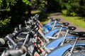 Rental ebikes standing in a row at charging station outdoors in bright summer sun