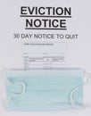 Rental eviction notice with blank covid 19 vaccine card plus facemask for eviction moratorium concept of financial hardships due Royalty Free Stock Photo