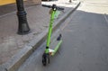 Rental green electric scooter parked on the sidewalk. Eco friendly urban transport