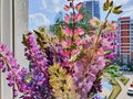 A colorful bouquet of wild flowers on the windowsill of a city apartment. Lupins flowers on urban background.