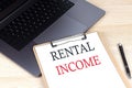 RENTAL INCOME text written on a paper clipboard on laptop Royalty Free Stock Photo