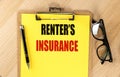 RENTER'S INSURANCE text on yellow paper on clipboard with pen and glasses