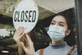 Reopen. friendly waitress wearing protection face mask turning closed sign board on glass door in modern cafe coffee shop, cafe re Royalty Free Stock Photo