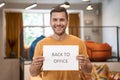 Reopening Business after lockdown. Young happy man showing paper with text BACK TO OFFICE at camera and smiling while Royalty Free Stock Photo