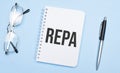 repa words in white notepad, pen and glasses on blue background. Concept Royalty Free Stock Photo