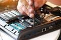 Repaiman with screwdriver fixing disassembled laptop parts. Technical support and fixing gadgets problems. Servicing Royalty Free Stock Photo
