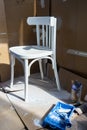 Repainting an old chair. Old white wooden chair, paint and brush.