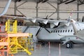 White passenger turboprop airplane under maintenance in the hangar. Repair of aircraft engine on the wing and checking mechanical Royalty Free Stock Photo