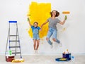 Repair in apartment. Happy family mother and child daughter jumping and paints wall Royalty Free Stock Photo