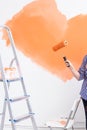 Repair in the apartment. Close-up of woman paints the wall with paint. Royalty Free Stock Photo