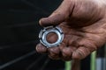 Repair bicycle wheel. Spoke key in the mechanic's hand. Rear wheel of a mountain bike on a black background. Dirty hands and Royalty Free Stock Photo