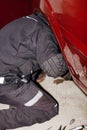 Repair of brake discs on a red car in the garage. The mechanic climbed under the wing of the car to remove the mount on Royalty Free Stock Photo