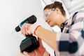 woman with perforator drilling wall at home