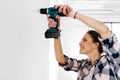woman with perforator drilling wall at home