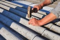 Repair dangerous asbestos old roof tiles. Worker installs asbestos roof shingles - closeup on hands.