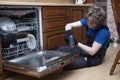 Repair of dishwashers. The master has come home and is repairing the dishwasher Royalty Free Stock Photo