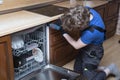 Repair of dishwashers. The master has come home and is repairing the dishwasher Royalty Free Stock Photo