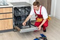 Repair of dishwashers. Repairman repairing dishwasher in kitchen Royalty Free Stock Photo