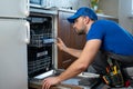 Repair of dishwashers. Repairman repairing dishwasher in kitchen Royalty Free Stock Photo