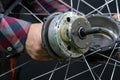 Repair of electric bicycles. A bicycle mechanic holds a wheel with an electric motor and a wrench in his hands. Bicycle wheel