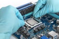 A repair engineer installs a processor chip into a circuit board socket