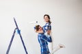 Repair, family and renovation concept - Funny young woman and man standing on the ladder