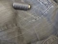 Repair garments, stitched seams on a worn jeans trousers with the sewing machine
