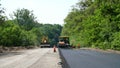 repair of a highway, roller compactor machine and asphalt finisher laying a new fresh asphalt pavement, covering on one Royalty Free Stock Photo