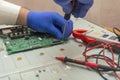 Repair of LCD TV in service center. Hands of engineer remove monitor parts with screwdriver and test it with multimeter. Selective