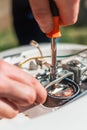 Repair and maintenance of the water heater. A man twists a screwdriver element of the water heater. Vertical orientation Royalty Free Stock Photo