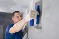 Repair master of concrete walls, plasters the joint of the wall with the ceiling, close-up