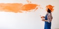 Repair in a new home woman repairman with a brush painted the wall with orange paint. Caucasian girl makes wall