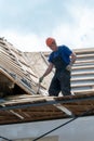 Repair of an old wooden roof. Replacement of tiles and wooden beams in an old house. A carpenter with tools in his hands is on the Royalty Free Stock Photo