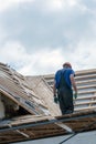 Repair of an old wooden roof. Replacement of tiles and wooden beams in an old house. A carpenter with tools in his hands is on the Royalty Free Stock Photo