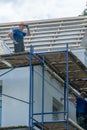 Repair of an old wooden roof. Replacement of tiles and wooden beams in an old house. A carpenter with tools in his hands is on the Royalty Free Stock Photo