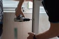 Repair of PVC windows. A worker installs a new pvc window mechanism using a drill. Selective focus, shallow depth of field Royalty Free Stock Photo