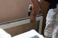 Repair of PVC windows. A worker installs a new pvc window mechanism using a drill. Selective focus, shallow depth of field