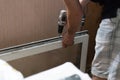 Repair of PVC windows. A worker installs a new pvc window mechanism using a drill. Selective focus, shallow depth of field Royalty Free Stock Photo