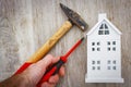 Repair and reconstruction of house concept. hammer, screwdriver in hand of builder and model of house on wooden background.