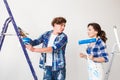 Repair, renovation and love couple concept - young family doing repair and painting walls together and laughing.