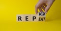 Repair and Repeat symbol. Hand turns cubes and changes the word Repeat to Repair. Beautiful yellow background. Businessman hand.