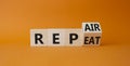 Repair and Repeat symbol. Turned wooden cubes with words Repeat and Repair. Beautiful orange background. Business and Repair and