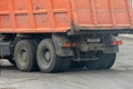 Repair of the roadway. The dump truck is working on the roadway, laying new asphalt. Big orange dump truck on new asphalt