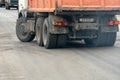 Repair of the roadway. The dump truck is working on the roadway, laying new asphalt. Big orange dump truck on new asphalt