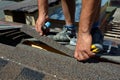 Repair of a Roofing from shingles. Roofer cutting roofing felt or bitumen during waterproofing works. Roof Shingles - Roofing. Royalty Free Stock Photo